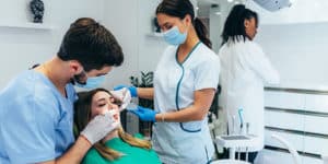 Un assistente dentista che grazie al corso professionale può assistere una paziente che sta curando i denti