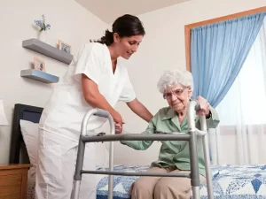 oss che aiuta un anziana che non deambula ad alzarsi grazie alle capacità acquisite durante il corso di formazione